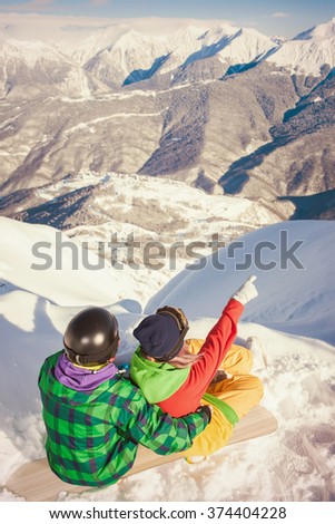Image of achieve couple of young man and woman snowboarder, skier on the background of Alps summit, Swiss mountains. Healthy lifestyle. Pointing to