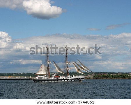 beautiful tall ship on ocean with blue sky and white puffy clouds