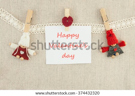 Valentine, greeting card. Wooden pins,  knitted loving couple man and woman, red heart,  lettering happy valentine's day hanging on a clothesline. On the cloth background