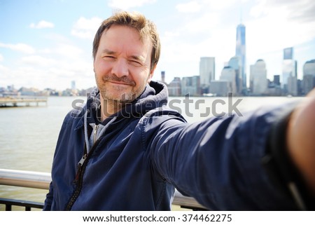 Middle age man making a self portrait (selfie) with Manhattan skyscrapers in New York City
