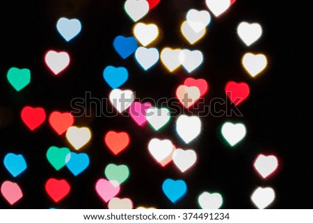 Valentine day blurred light colorful heart on black background.