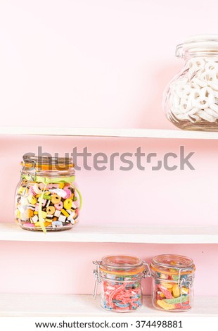 Colorful candies in jars on shelf.