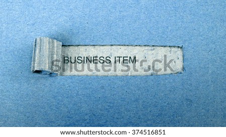   Torn blue paper on dull blue surface with "business item"                             