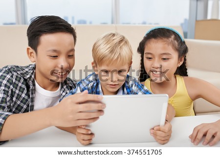 Preteen kids gathered in front of digital tablet