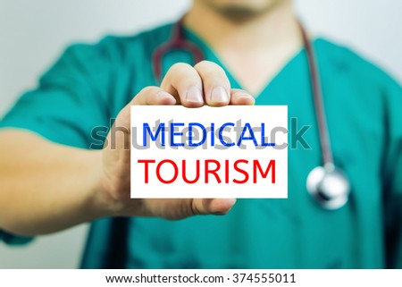 Doctor holding a  business card with capital lettering MEDICAL TOURISM in hand.Medical concept,  Selective focus.vintage tone.