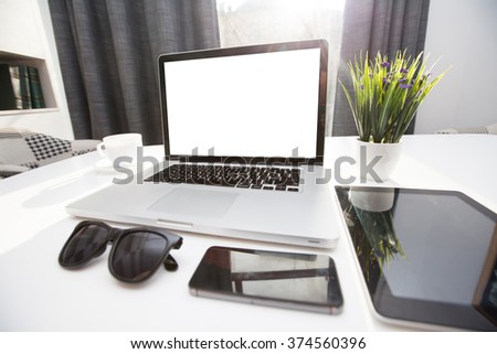 Office desk next to a window with laptop and tablet pc and a smart phone