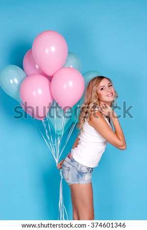 Young beautiful blonde girl holding balloons. Studio. Woman holding colorful balloons. Birthday.