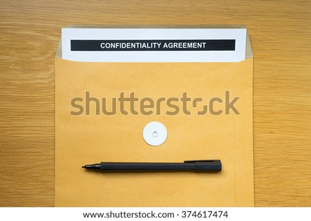 "Agreement" paper in brown envelope with black pen on wood table background.