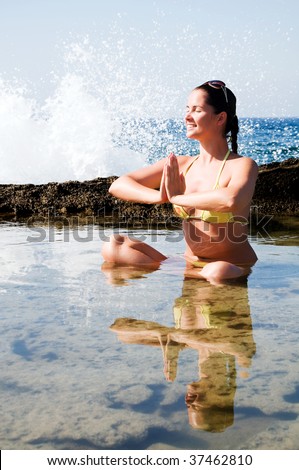 Beautiful young woman doing yoga at the sea