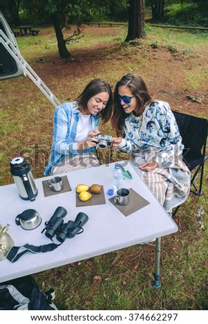 Young woman taking photo to happy friend while having a breakfast in campsite