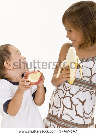 Two young kids have fun while eating fresh fruit.