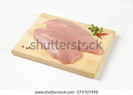 raw turkey breasts with spice and herbs on wooden cutting board
