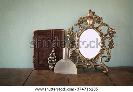 Antique blank Victorian style frame and old book with vintage pearl necklace on wooden table. retro filtered image. template, ready to put photography
