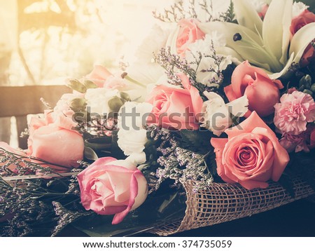 Beautiful bouquet pink roses and carnation flower on wooden table with sunlight.Vintage style photo and filtered process.