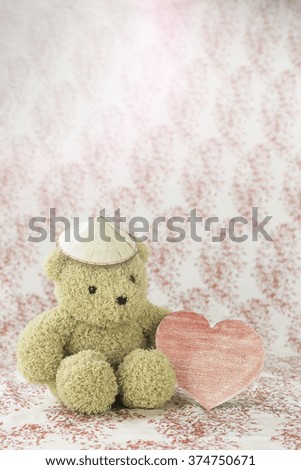 teddy bear hold the red paper heart on color background with flare light for valentine's day
