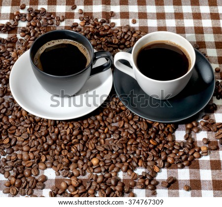 Top view of two coffee cups and coffee beans on a checkered cloth