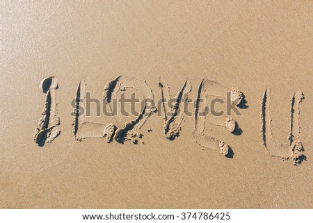 Word "I love U" hand written on a beach.