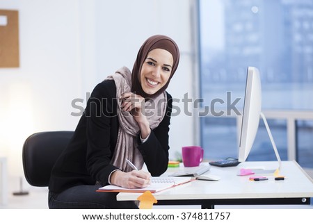 Beautiful Arabic business woman writes in a notebook in her office