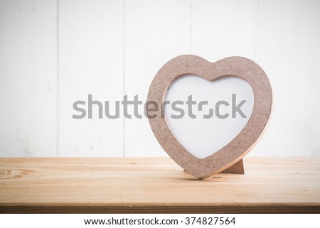 Heart shaped photo frame on wood table