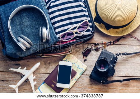 Clothing traveler's Passport, wallet, glasses, smart phone devices, on a wooden floor in the luggage ready to travel. Royalty-Free Stock Photo #374838787