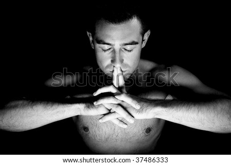 young caucasian man in meditation on black background
