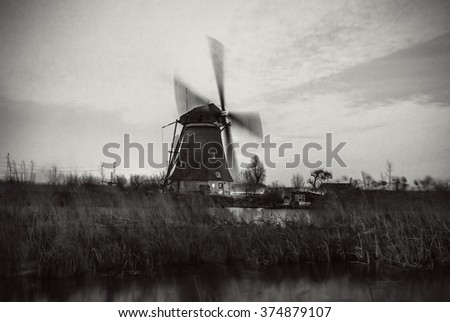 Windmills and water canal on sunset in Kinderdijk, Holland. Black-white photo.