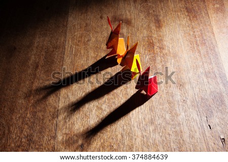 Three Origami paper bunny rabbits isolated on wooden background