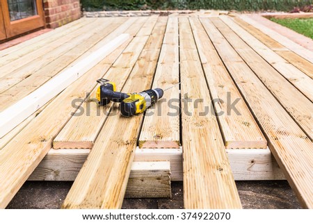 A new wooden, timber deck being constructed. it is partially completed. a drill can be seen on the decking. Royalty-Free Stock Photo #374922070