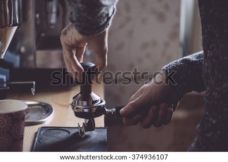 Man tamping fresh morning coffee Royalty-Free Stock Photo #374936107