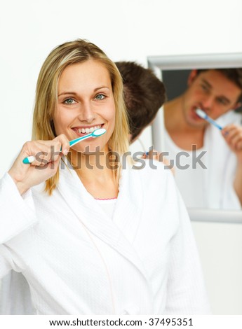 Smiling woman cleaning her teeth with her boyfriend in bathroom
