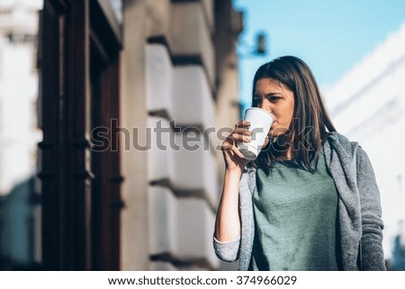 Girl drinking take-away coffee, city street
