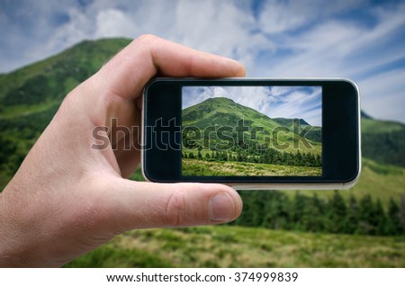 Cell phone in hand and country view of sunny day