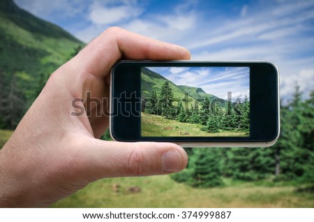 Cell phone in hand and country view of sunny day, take pictures on the phone picture on your smartphone, on the background of mountain scenery