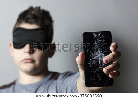 sad teen with sleep mask is worried because of breakage glass of smart phone in front of grey background