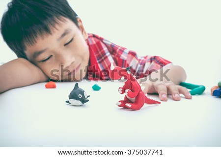 Asian handsome child sleeping with his works from clay, on white background. Strengthen the imagination of child. Vintage picture style. Selective Focus (model clay in focus).