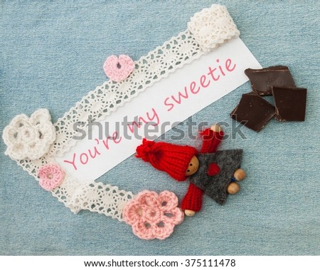 Valentine greeting card with pink and red hearts, chokolate and  knitting enamored man. Lettering YouÃ¢??re my sweetie on the denim background.