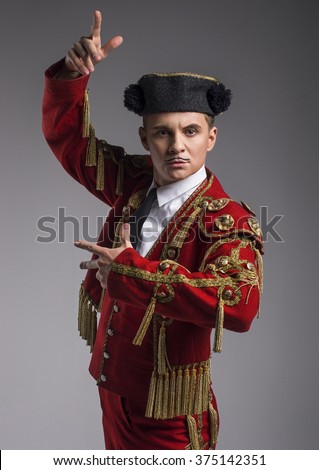 Studio shot of man dressed as Spanish torero, matador, bullfighter. Performing a traditional classic bullfight, standing and holding the capote. Royalty-Free Stock Photo #375142351