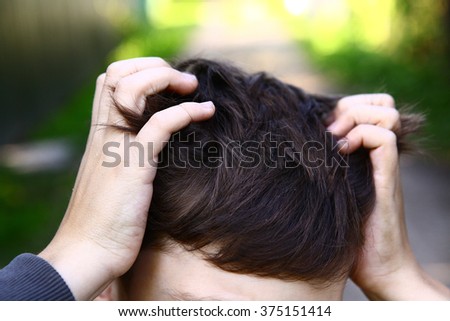 boy itching scratching his head caused by lice parasites  invasion