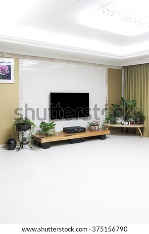 Living room with smart television(TV, LED, LCD, HD, Full HD, UHD, display), gold wall, white marble stone, wood table, audio, green plant pot, flower pot, picture.