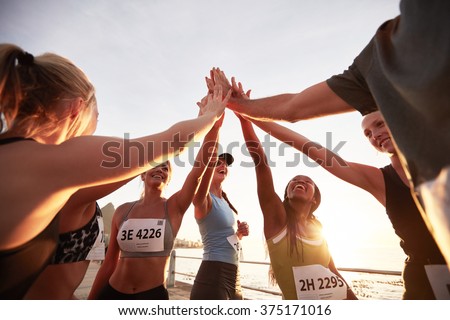 Runners high fiving each other after a good training session. Group of athletes give each other high five after race. Royalty-Free Stock Photo #375171016