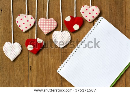 Valentine's hearts and open notebook with white lined pages on wooden background