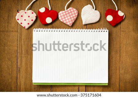 Valentine's hearts and open notebook with white lined pages on wooden background,vignette lens style