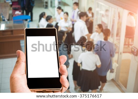 Hand holding  Black Smartphone with blank screen on blur background  office or university or hospital