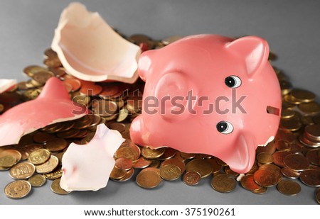 Broken piggy bank with pile of coins on grey background, close up