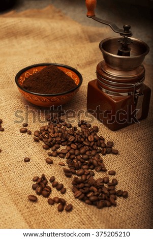 Still life with coffee beans, coffee mill  on the background of sackcloth. Toned image.