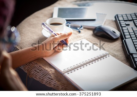 woman left hand writing on paper book ,on table shot Royalty-Free Stock Photo #375251893