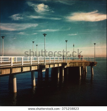 Vintage edited picture  Old wooden pier over the sea shore 