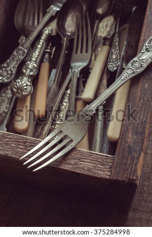 Vintage fork and a drawer box of cutlery in the background with a vintage filter applied to image