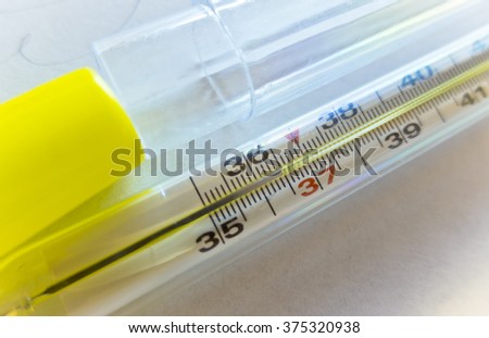 Glass and fragile mercury thermometer to measure the analog scale in Celsius shows the standard human body temperature with a plastic cover Royalty-Free Stock Photo #375320938