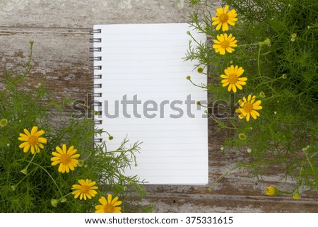 Blank Notepad and flower on wooden table, Plant and garden background concept.